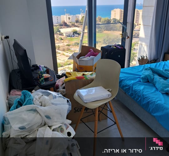 חדר מבולגן עם נוף לים, מיטה, כיסא וארגזים